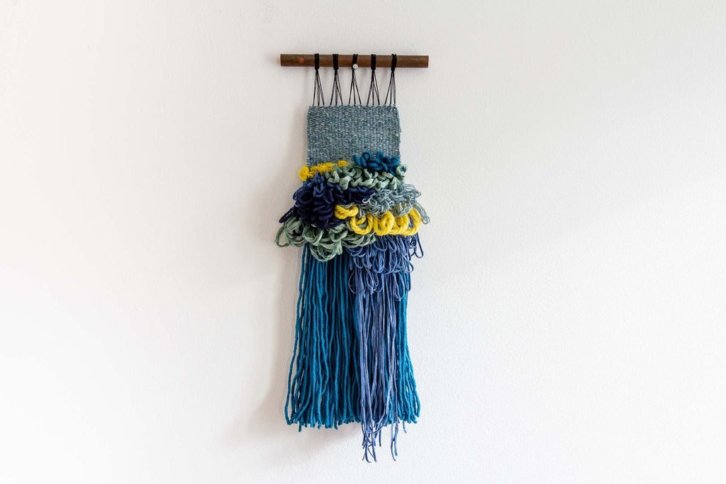 Rock pool is a small woven wall hanging which is made of fibres in sea green, blue, turquoise and yellow