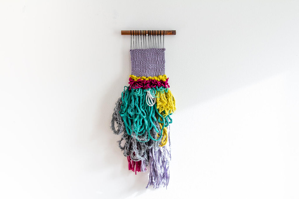 Fiesta woven wall hanging. Grey, purple, green and chartreuse makes this a vibrant little wall hanging.